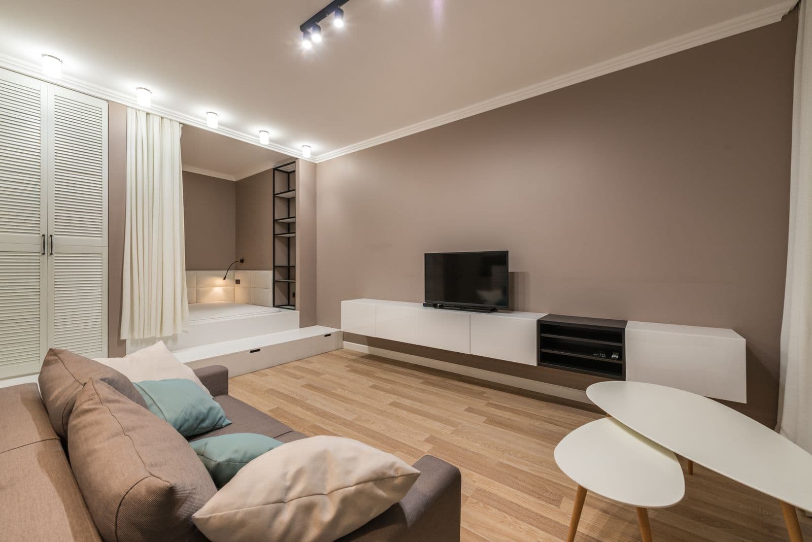 Warm living room with a sofa, wood floor, and built-in storage