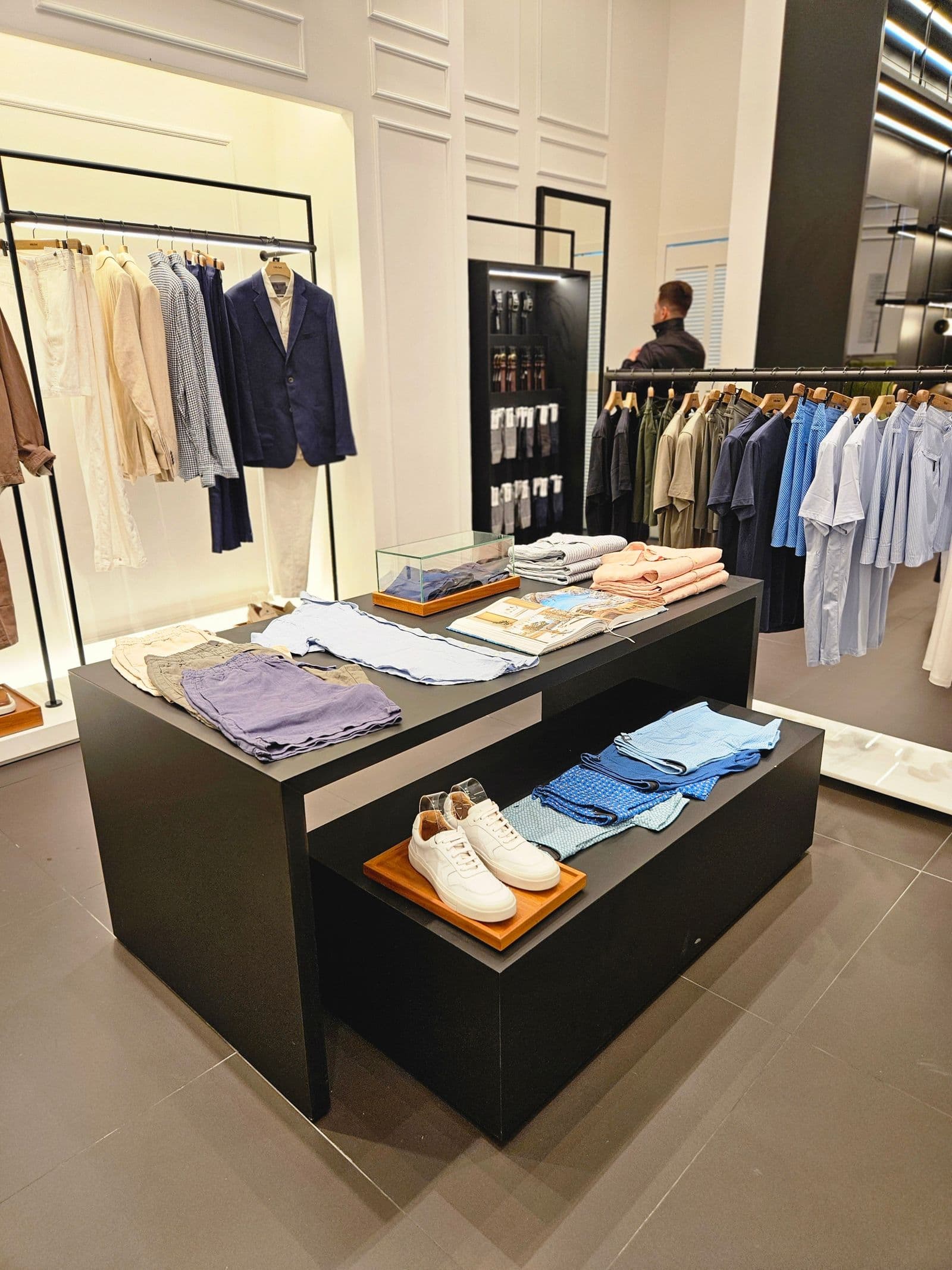 Clothing boutique with display tables and illuminated racks